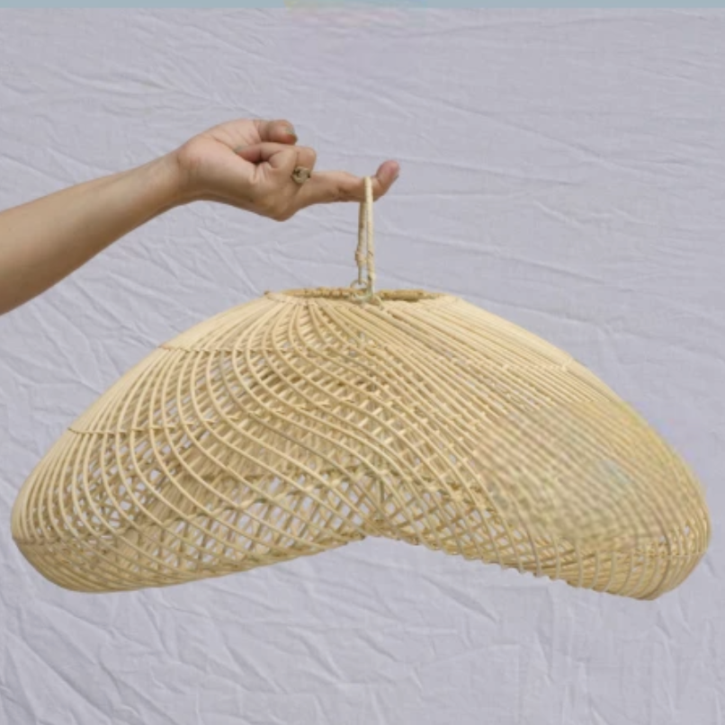 Suspension en rotin naturel sur fond gris porté par le doigt d'une personne