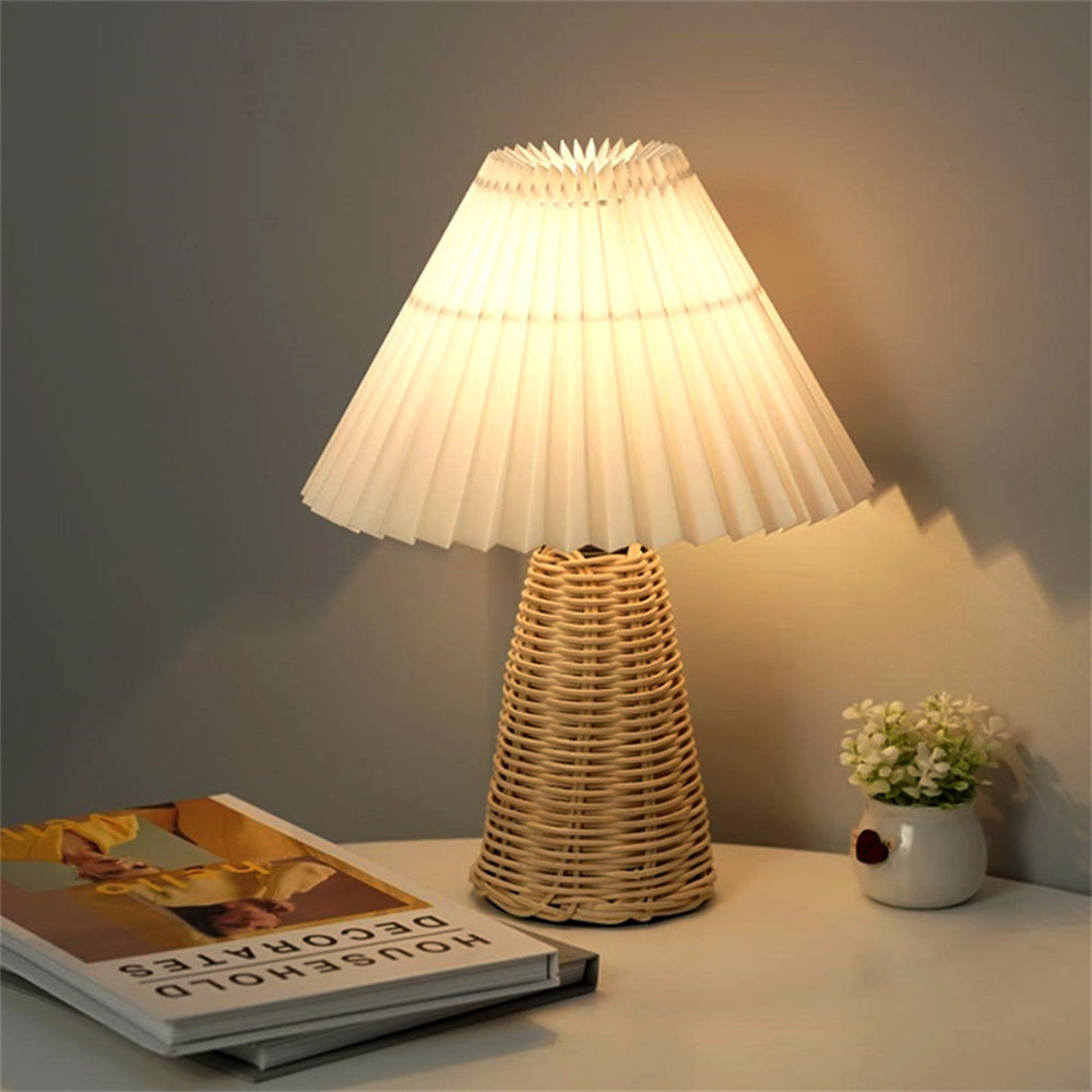 Lampe de chevet rotin avec abat-jour plissée blanc allumé sur une table près de livres